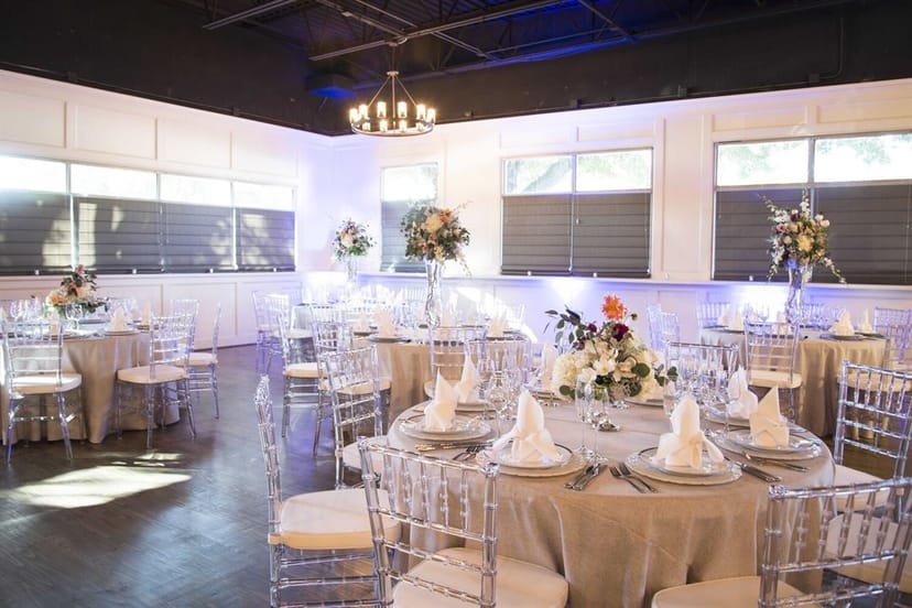 Elegant wedding venue with round tables, floral centerpieces, and ambient lighting.