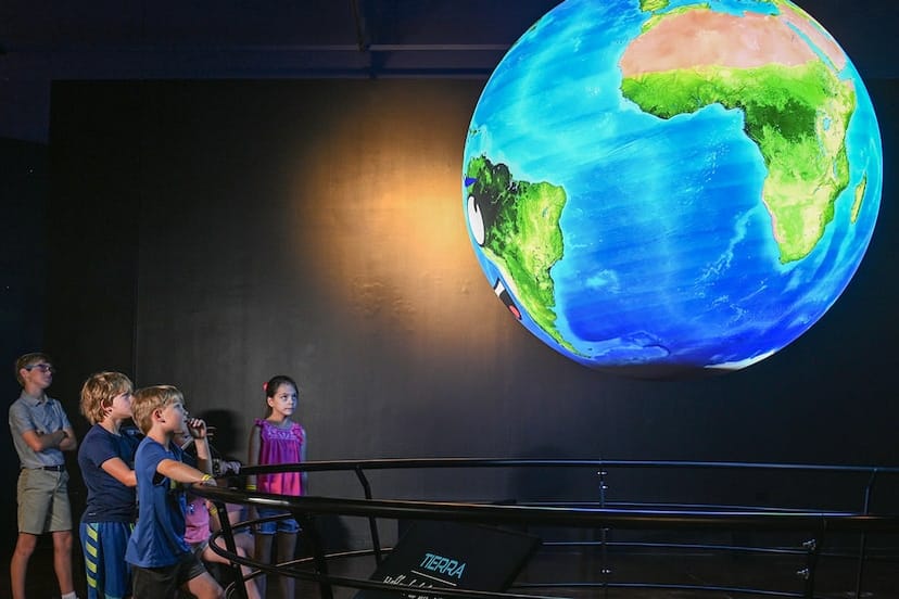 Children interacting with an interactive globe at Fort Worth Planetarium for educational events.