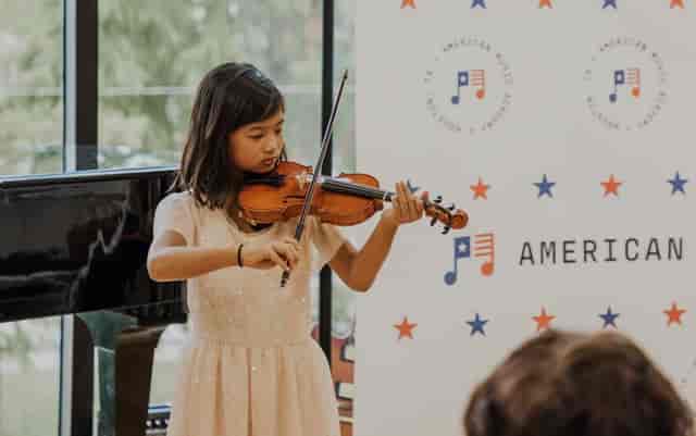Young violinist performing at AMA Houston event, enhancing guest experience through live music.
