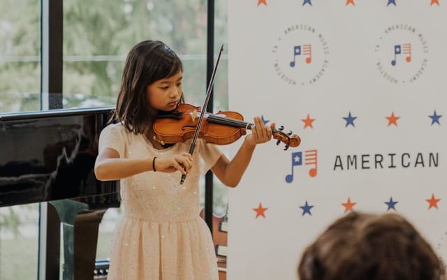 Young violinist performing at AMA Houston event, enhancing guest experience through live music.