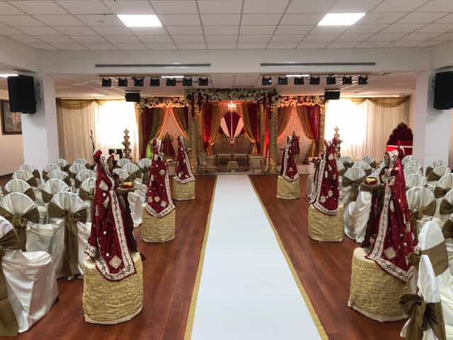 Elegant Radha Krishna Temple ballroom, decorated in gold and red for weddings and events.