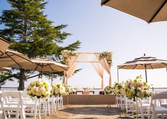 Elegant outdoor wedding ceremony at The Overlook, featuring floral arch and white chairs.