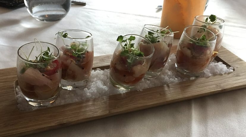 Elegant seafood appetizers in shot glasses at Alexander's Steakhouse bar, perfect for upscale events.