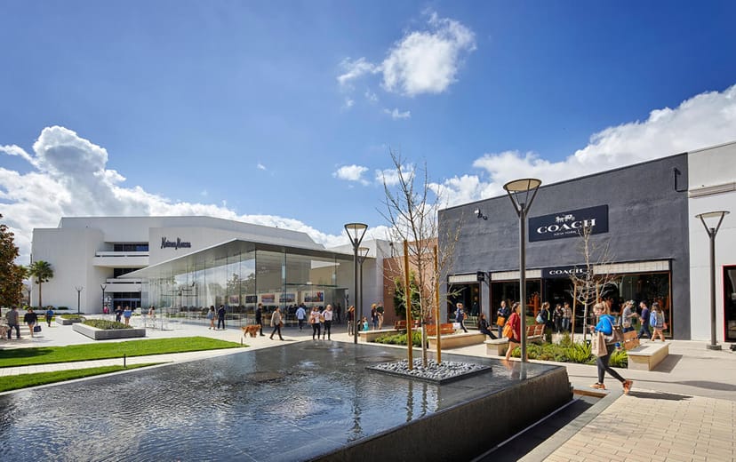 Outdoor shopping mall at Stanford, showcasing modern architecture and serene water feature.