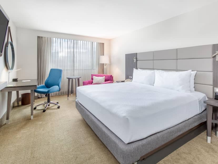 Modern hotel room in Crowne Plaza ideal for meetings, featuring a large bed and natural light.