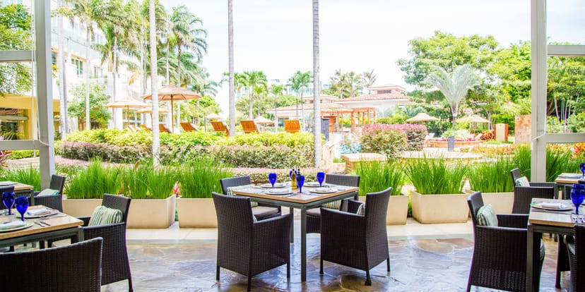 Outdoor dining area with lush greenery at Arboleda, perfect for events and meetings.