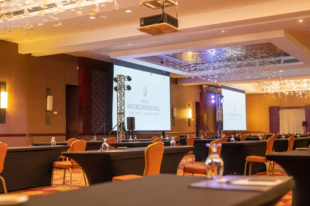 Conference center with rows of tables and AV setup, perfect for corporate events.