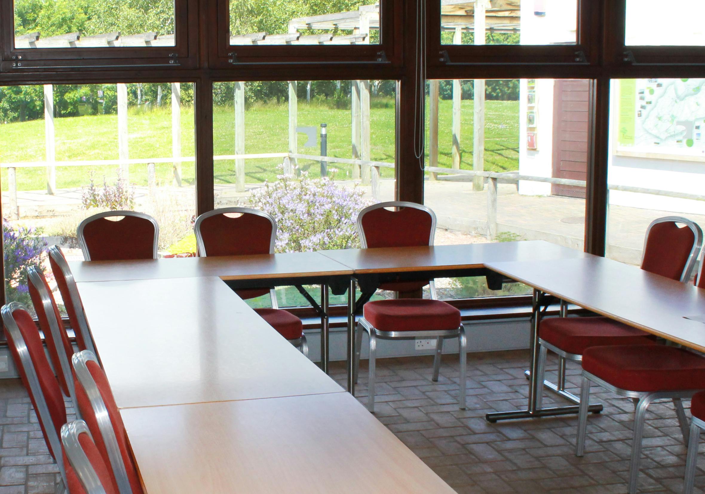 Bright meeting room at The Folly, featuring U-shaped table and large windows for events.