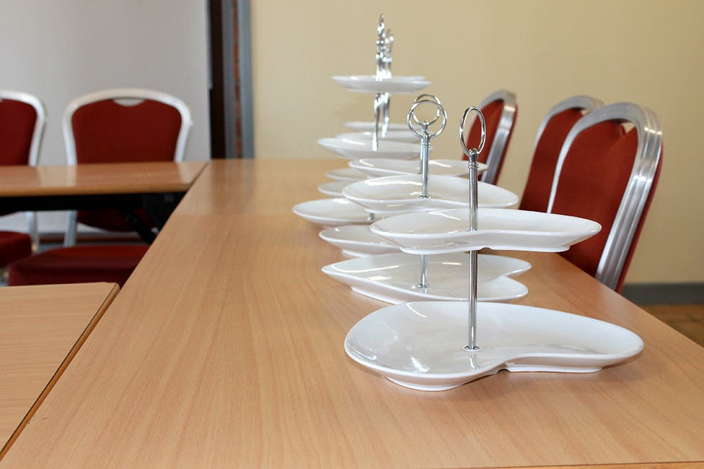 Neatly arranged event table with tiered platters and red chairs at The Folly, Forest Centre.