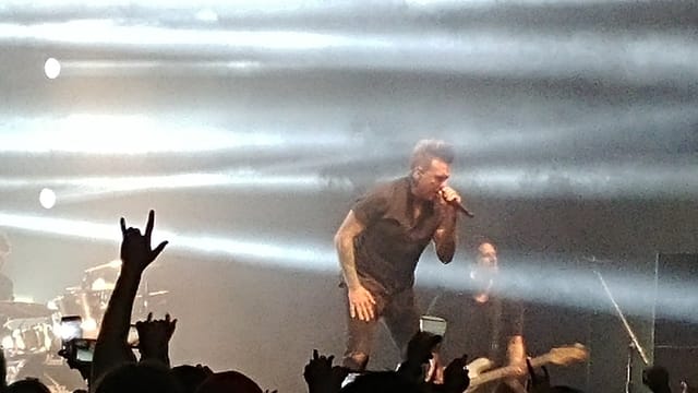 Dynamic live performance in a ballroom with dramatic lighting and enthusiastic crowd.