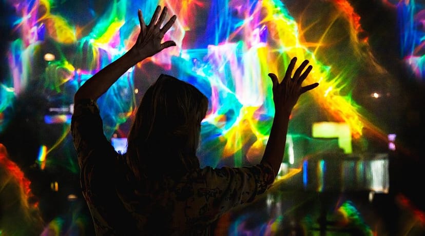Individual enjoying vibrant light display at Utopia Club's amusement center for events.
