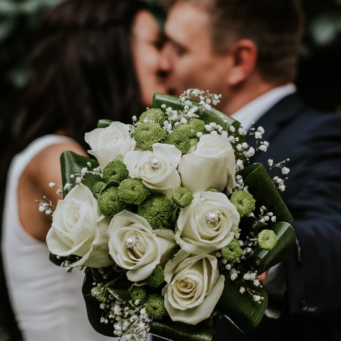 Couple's romantic wedding moment with vibrant bouquet at South Bay Event Center.