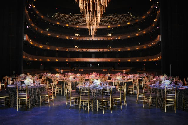 Elegant event space with floral centerpieces and chandelier in Winspear Opera House.