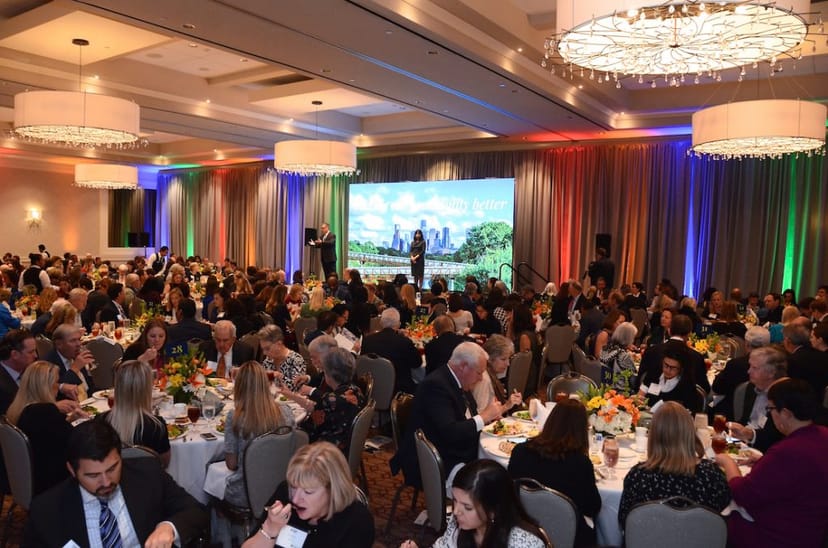 Elegant banquet hall set for a vibrant gala with floral centerpieces and uplighting.