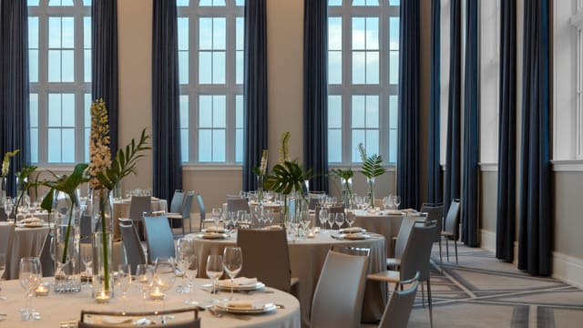 Elegant meeting space with round tables and floral decor for weddings and corporate events.