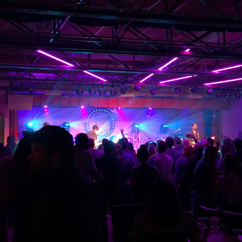 Live band performing in vibrant Deep Ellum backyard with colorful lighting at music event.
