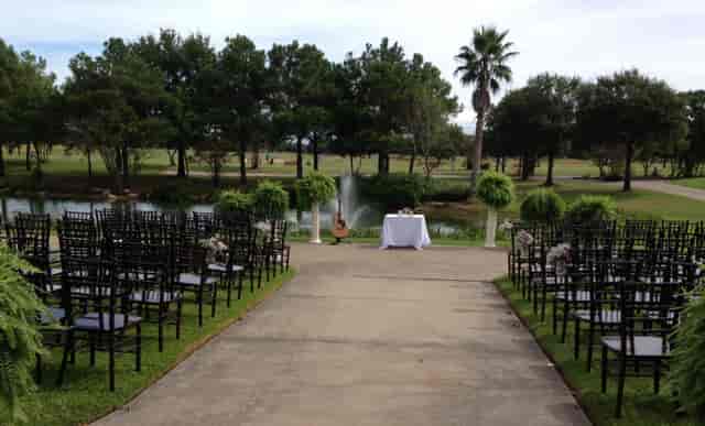 Elegant banquet hall with black chairs, lush greenery, perfect for outdoor ceremonies.