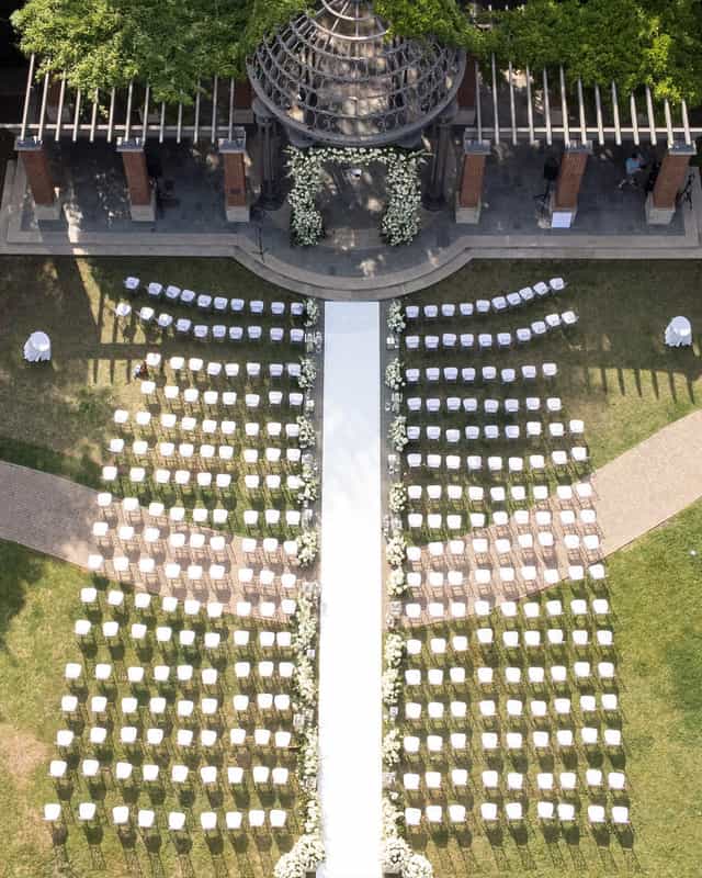 Outdoor wedding setup in Arlington Hall's Formal Garden with white chairs and floral decor.