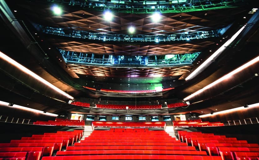 Sleek theater auditorium with tiered red seating, ideal for performances and conferences.