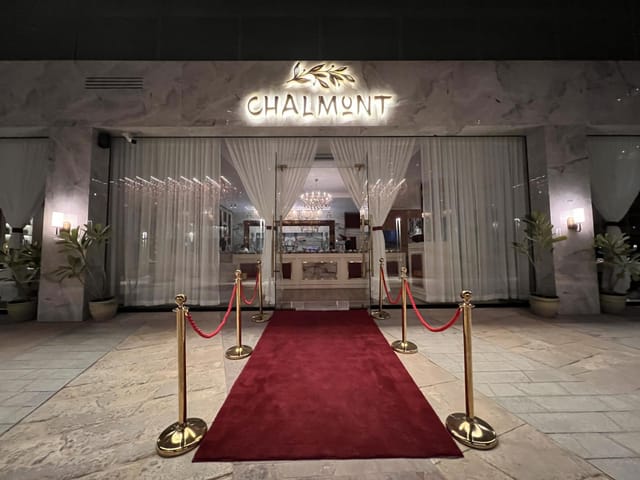 Elegant banquet hall entrance with red carpet and gold stanchions for upscale events.