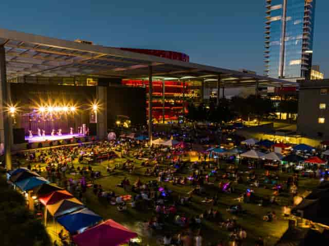 Vibrant outdoor event at Annette Strauss Square with bright lights and audience on lawn