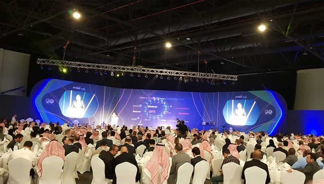Dhahran Expo banquet event with attendees at round tables and a stage backdrop.