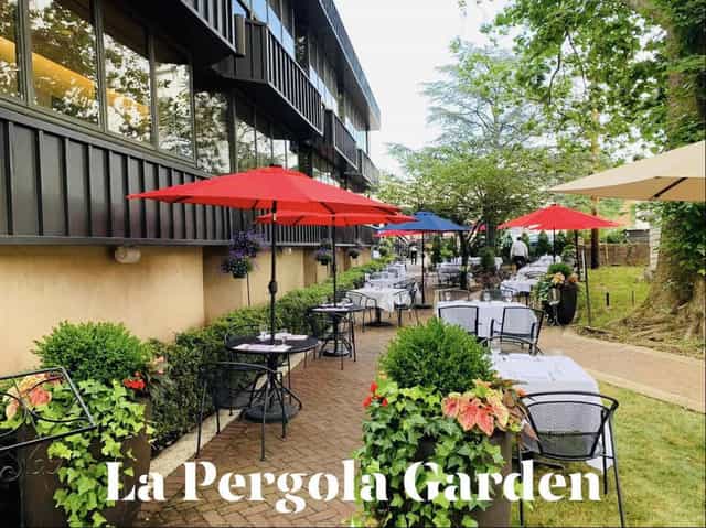 Charming outdoor dining area at La Pergola Garden with vibrant umbrellas for events.