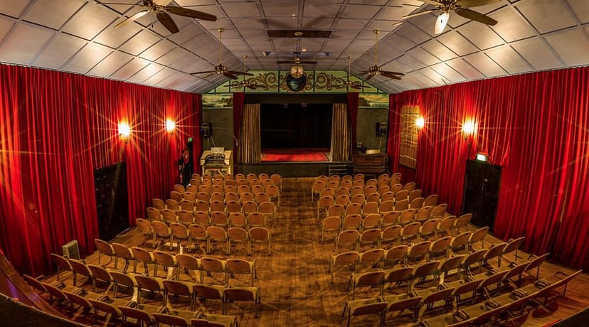 Intimate Majestic Theatre with red drapes, perfect for presentations and performances.