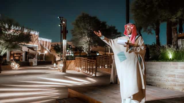 Welcoming host in traditional attire at Bujairi Terrace outdoor event space.