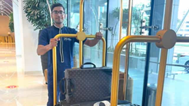 Corporate staff member assisting with luggage in a sleek MUFEED office event space.