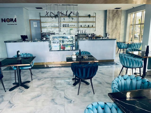 Modern cafe in Al Waha Hotel with elegant blue chairs, ideal for networking events.