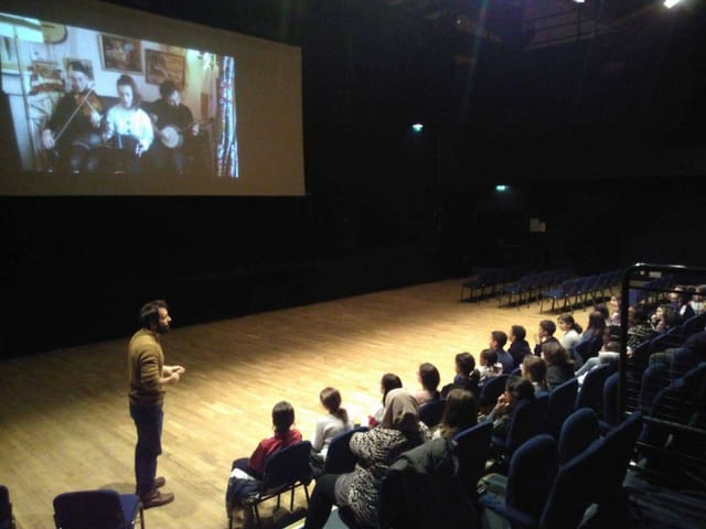 Concert hall audience engaged in a workshop presentation with interactive seating.