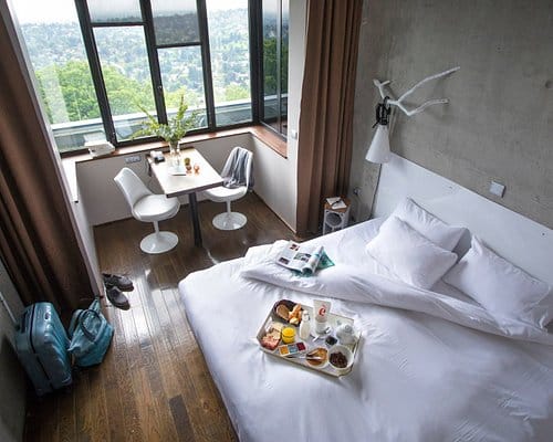 Stylish hotel room at La Maison, featuring a cozy bed for retreats and meetings.