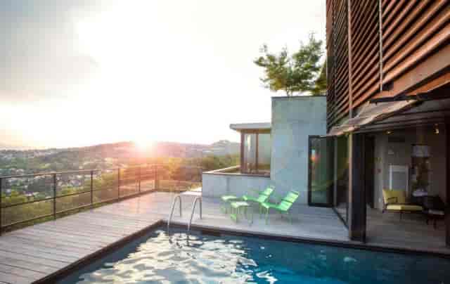 Modern outdoor event spaces at La Maison, Ermitage Hotel with inviting pool and lounge chairs.