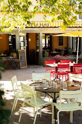 Outdoor café at Café de la Place with vibrant chairs for casual meetings and networking.