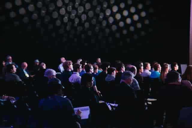 Engaged audience at Salle Bruxelles conference with dynamic lighting, networking event