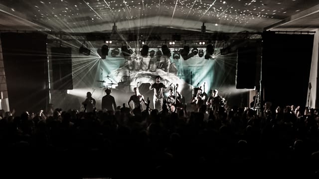 Energetic concert at Les Abattoirs SMAC with vibrant crowd and dramatic lighting.