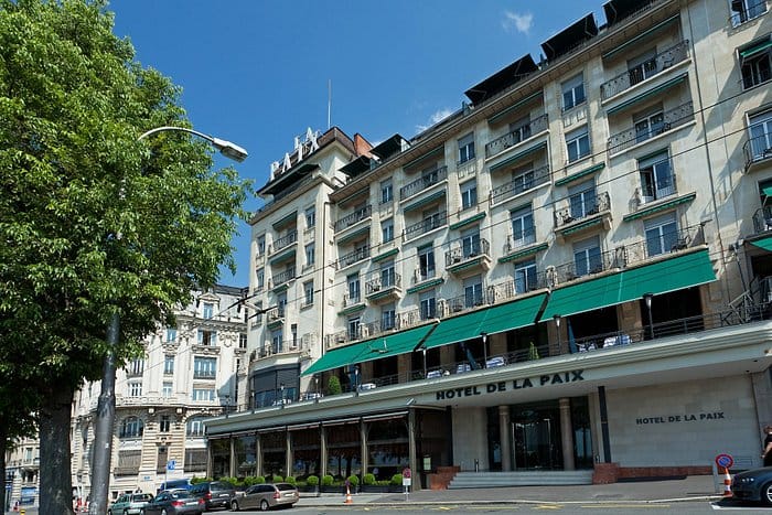 Charming Hôtel de la Paix facade, ideal for meetings and events, with outdoor seating.