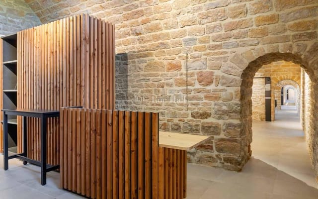Underground event space in Fort de Vaise with wooden finishes and stone walls.