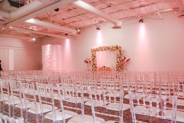 Elegant Nuvo Room wedding banquet hall with floral arch and transparent chairs.