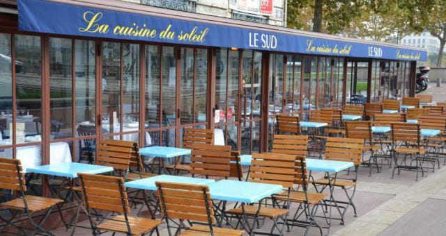 Outdoor dining at Brasserie Le Sud with blue tables, perfect for casual meetings and events.