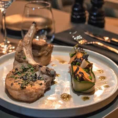 Plated pork chop with vegetables at Le Bistrot, ideal for upscale events and dining.