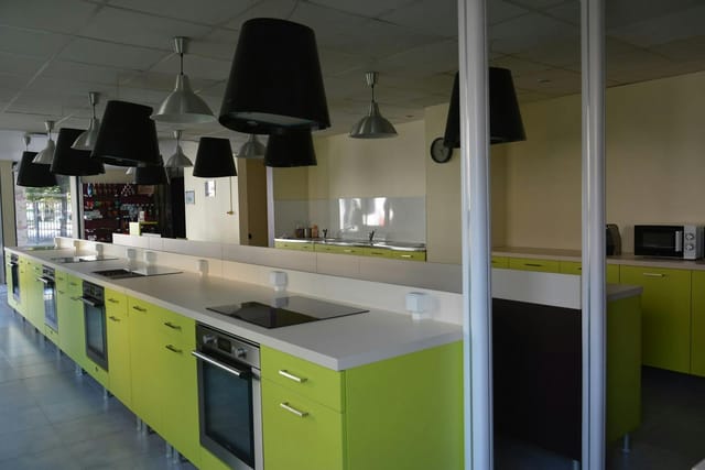 Modern catering kitchen with green cabinetry, ideal for cooking classes and events.