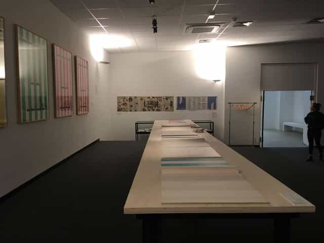 Art exhibition in Institut d'art contemporain auditorium, featuring a long display table.