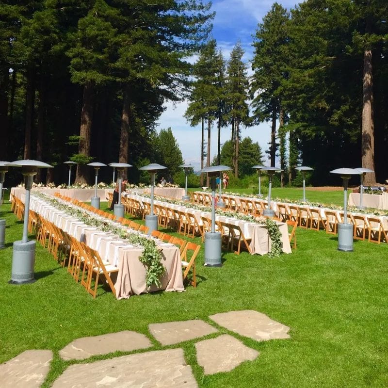 Elegant outdoor wedding setup with tables and floral centerpieces in a forest.