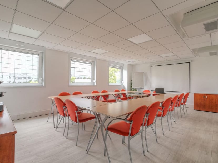 Training room with central table and orange chairs, ideal for meetings and presentations.