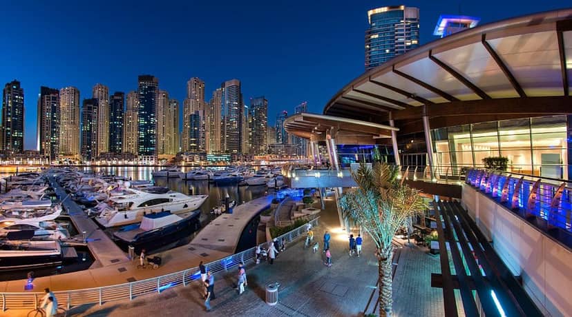 "Club House Marina at Dubai Marina: upscale event space with illuminated skyline and yachts."