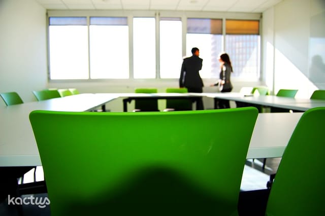 Modern meeting room with green chairs, ideal for productive workshops and discussions.