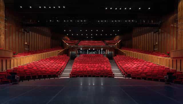 Grande Salle in Maison de la Danse with tiered red seats, perfect for conferences and performances.