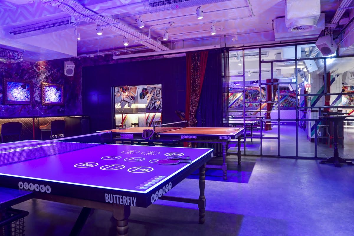 Vibrant event space with illuminated ping pong tables for networking in Shoreditch. - Banner